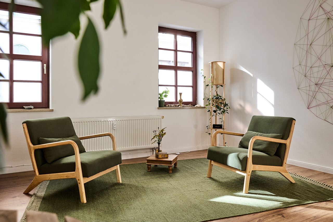 Zwei grüne Sessel mit einem kleinen Tisch, Pflanzen und Tageslicht